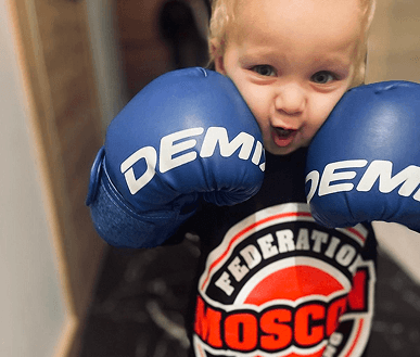 Маленький боксер в синих перчатках с логотипом федерации