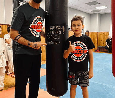 Тренер с учеником рядом с боксерским мешком